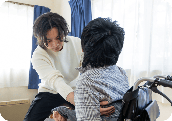 ベットから被介護者が介護士に移動してもらうシーン